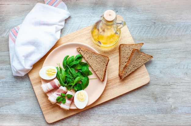 Bord met spinazieblaadjes basilicum spek eieren en roggebrood Olijfolie Gezond ontbijt Eten Plat leggen