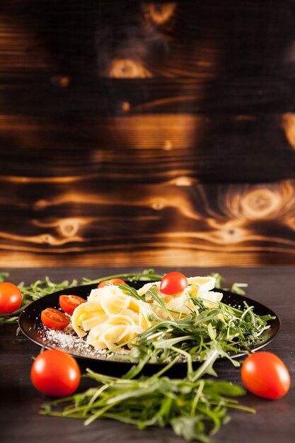 Bord met tagliatelle pasta naast cherrytomaatjes op houten achtergrond