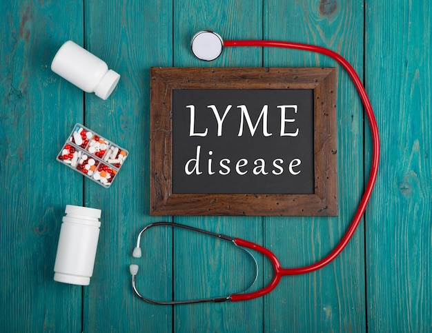 Bord met tekst Lyme-ziektepillen en stethoscoop op blauwe houten achtergrond