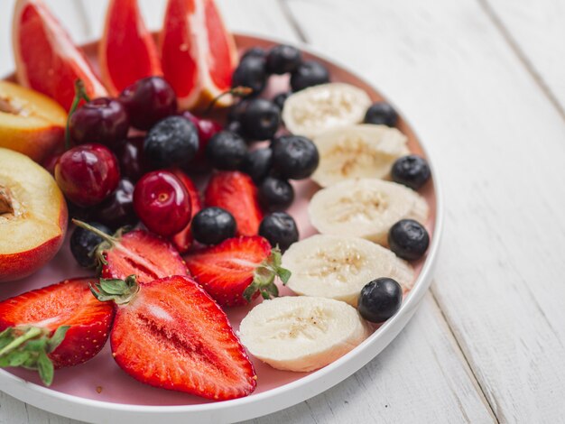 Bord met vers zomerfruit. Aardbei, bosbes, zoete kers op houtwit