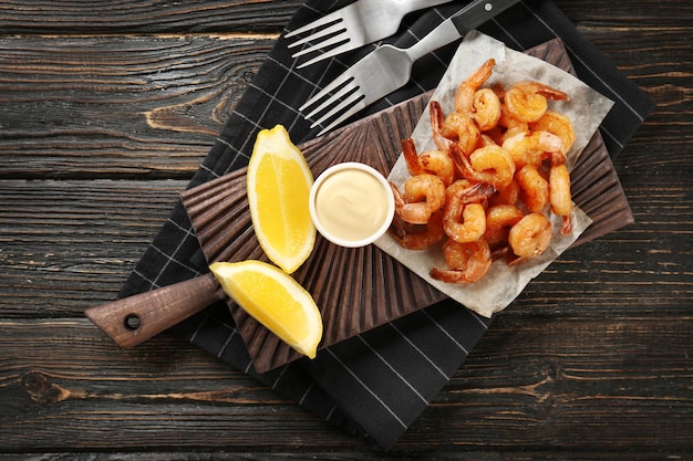 Foto bord met verse smakelijke garnalenmand en saus op tafel