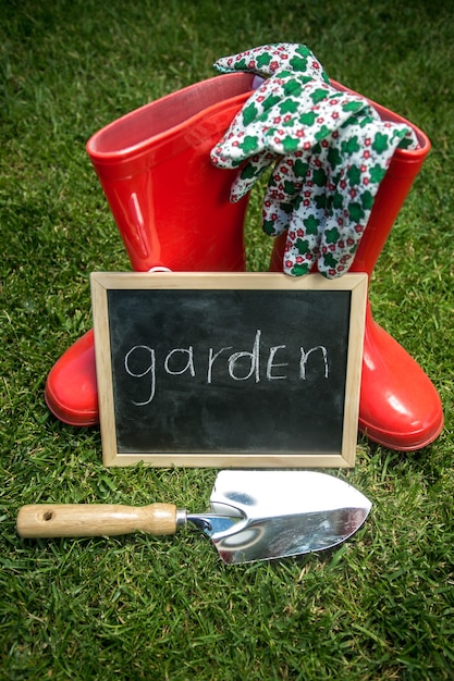 Bord op het verse groene gras naast tuinhulpmiddelen met tekst "Tuin"