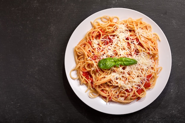 Bord pasta met tomatensaus en Parmezaanse kaas op donkere achtergrond, bovenaanzicht