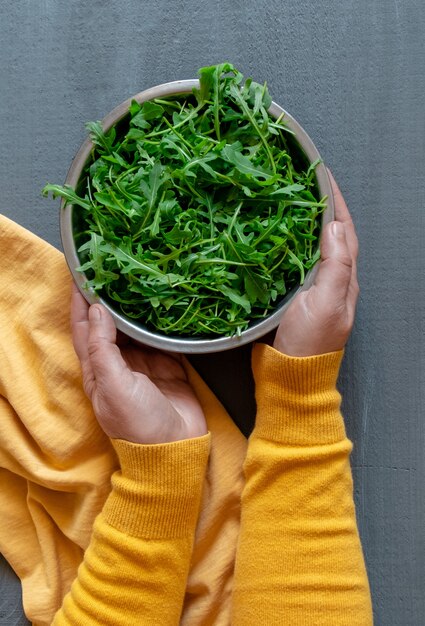 Bord rucola groene hand geel grijze achtergrond kopie ruimte fortuna gouden kleur