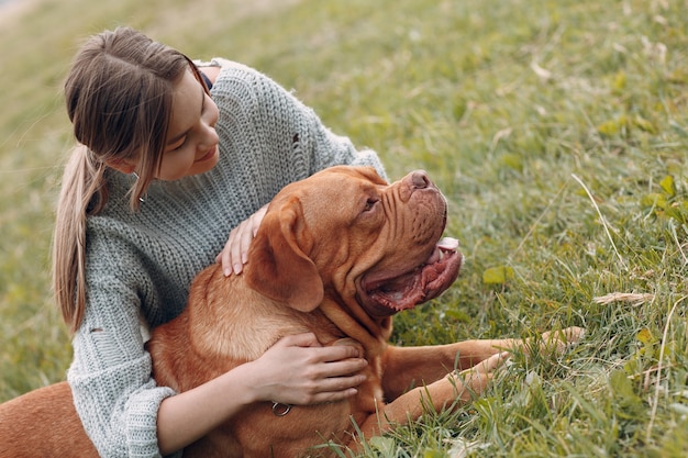 Bordeauxdog of Franse Mastiff met jonge vrouw bij openluchtparkweide.