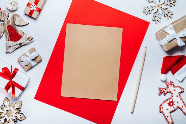 Foto bordo di decorazioni natalizie e scatole regalo con un pezzo di carta bianca per scrivere i desideri delle vacanze. vista dall'alto, piatto.