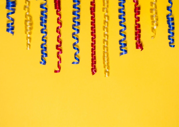 Border of colored festive ribbons on a yellow background Gift scenery