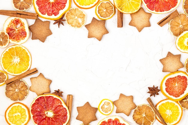 Border of Dried slices of various citrus fruits gingerbread and spices on white background with copyspace