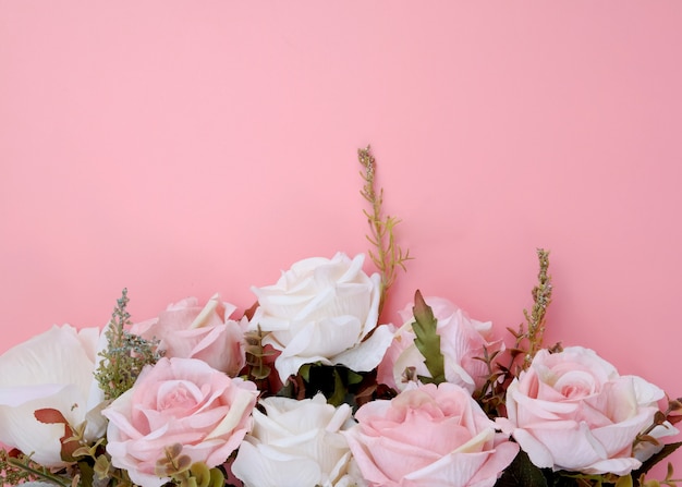 Border frame made of pastel pink rose flowers on pink background