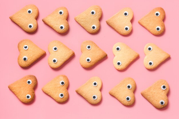 Border of homemade heart shaped cookies on pink. Flat lay.