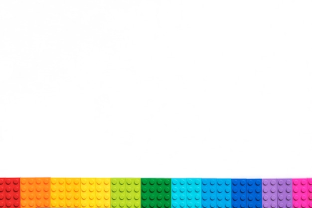 Border of Multicolor Plastick constructor bricks on white background. Popular toys.