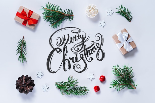 Border of new year decorations and pine tree branches on white background with Merry Christmas wishes written with calligraphic font