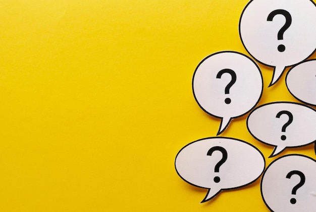 Photo border of question marks in speech or thought bubbles over a vivid yellow background with copy space