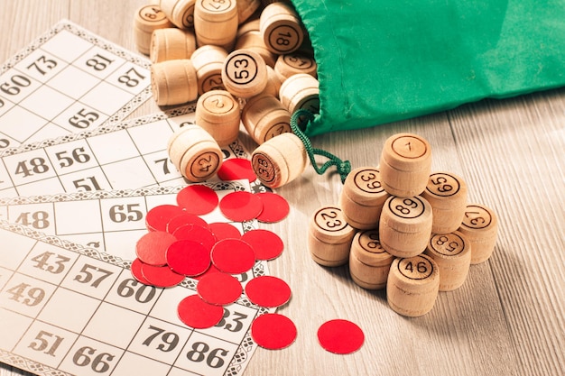 Foto bordspel lotto. houten lotto-vaten met groene zak, rode fiches en speelkaarten voor een spel in lotto