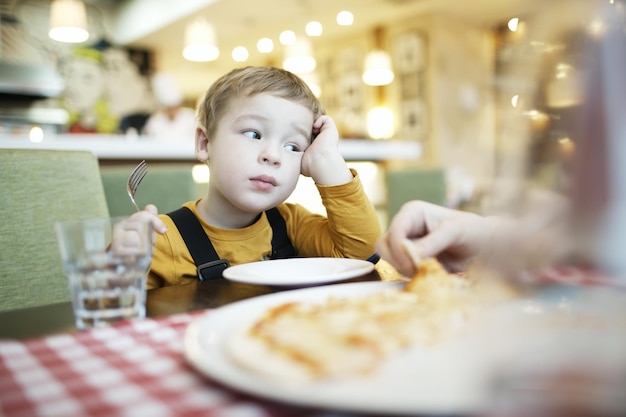 Bored boy sitting on chair in restaurant