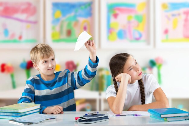 写真 テーブルのそばに座って目をそらす退屈な子供たち