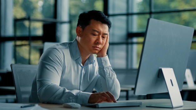 Скучающий ленивый азиатский рабочий бизнесмен корейский японский мужчина измученный усталый мужчина сидит в офисе спит