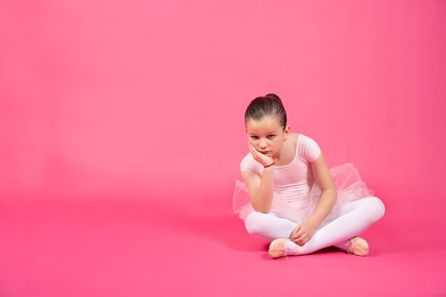 Bored little dancer girl sitting and looking at camera