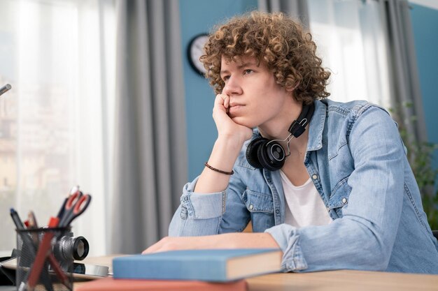 Bored male student in headset sit at desk study making notes focused man in headphones