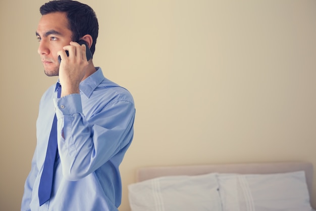 Bored man calling someone withmobile phone and looking away