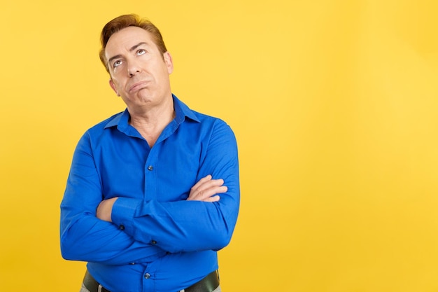 Bored mature man looking up with arms crossed