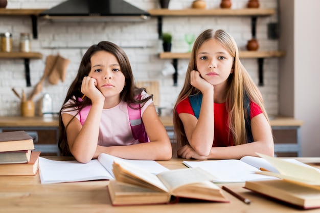 Фото Скучающие многонациональные школьницы делают домашнее задание