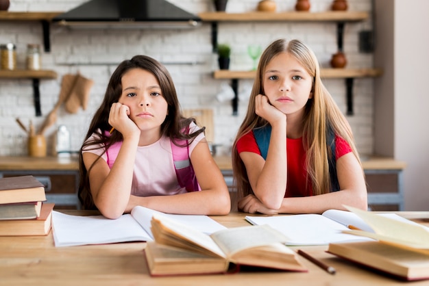 Photo bored multiethnic schoolgirls doing homework