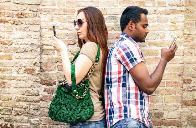 Bored multiracial couple using mobile smart phone