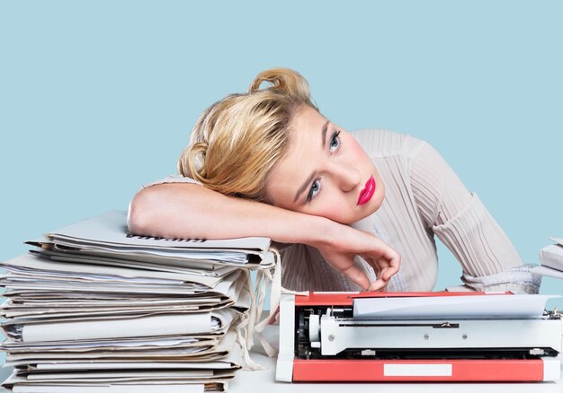 A bored office worker sitting behind a large stack of paperwork