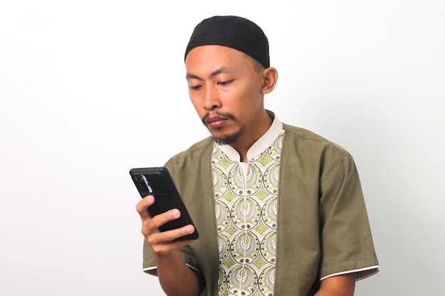 Нудный во время Рамадана индонезийский мужчина проверяет телефон