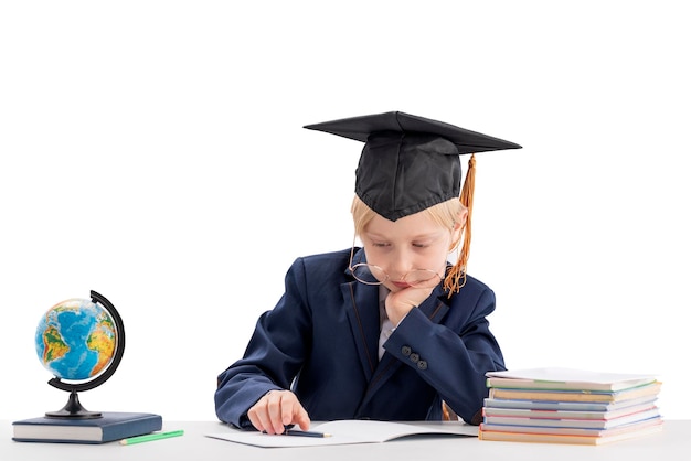 Bored schoolboy in students hat does his homework Tired schoolboy isolated on white background