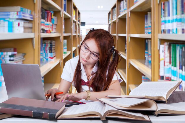 Photo bored student doing homework in library