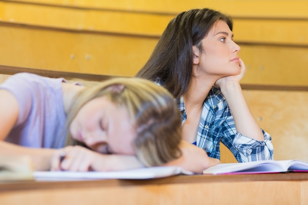 Foto studente annoiato che ascolta mentre compagno di classe che dorme nell'università