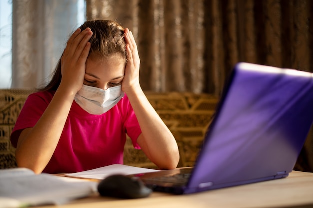 Studente annoiato che lavora al computer. i giovani studenti delle scuole hanno studiato a casa, malati e stanchi di apprendere via internet tutto il giorno