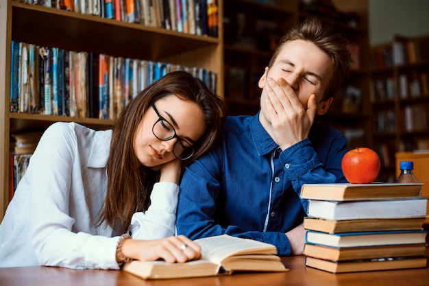 Gli studenti annoiati stanchi di studiare costantemente si sono addormentati mentre lavoravano al progetto tutto il giorno