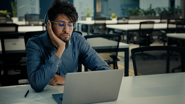 Bored tired arabian indian ethnic man businessman sit at office desk exhausted lazy sad male in