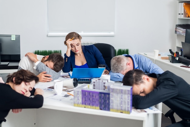 Bored or tired business people sleeping, resting on their workplace during the meeting