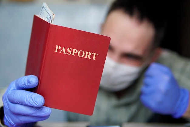 Foto un turista annoiato viene messo in quarantena a casa, indossando una maschera e guanti, guardando il passaporto e i soldi. i collegamenti aerei sono stati annullati a causa del coronavirus. vacanza annullata a causa della pandemia di covid-19