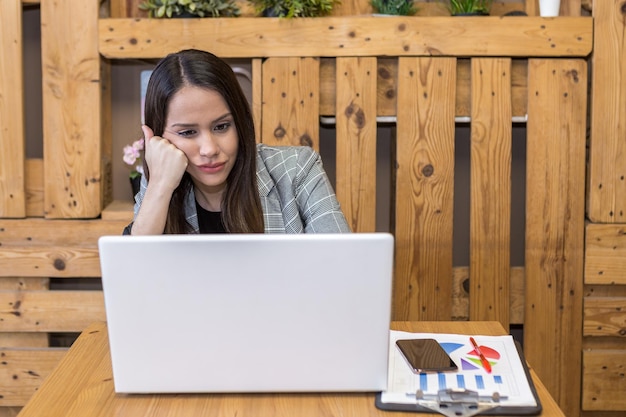 Bored woman leaning on hand while using laptop