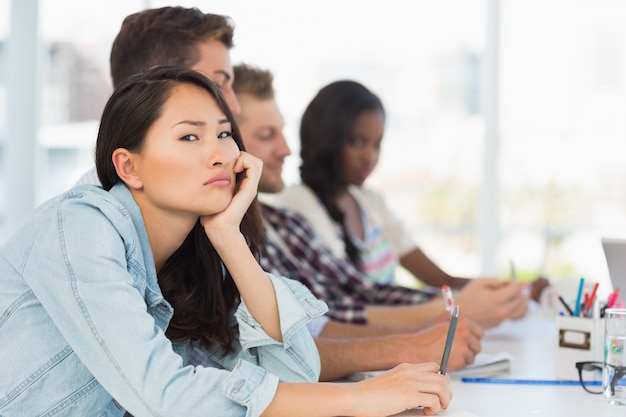 Bored woman looking at camera during a meeting in creative office