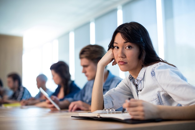 Bored woman sitting in meeting room with her colleagues