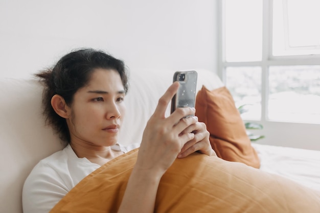 Bored woman use smartphone social media for killing time in apartment