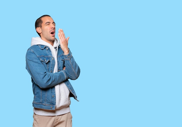 Bored young man doing yawning gesture