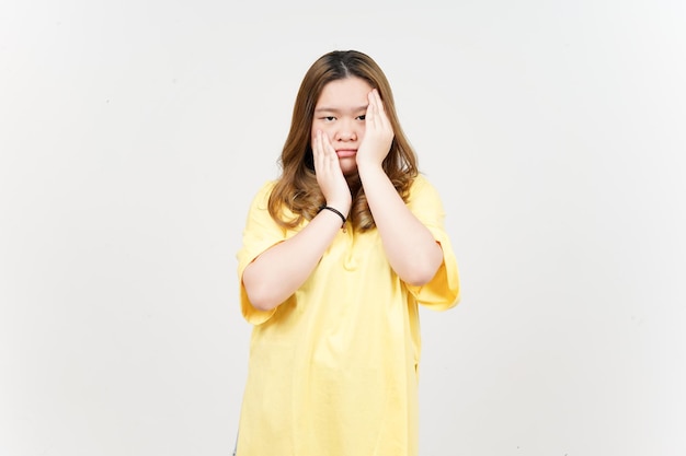 白で隔離黄色のTシャツを着ている美しいアジアの女性の退屈なジェスチャー表現