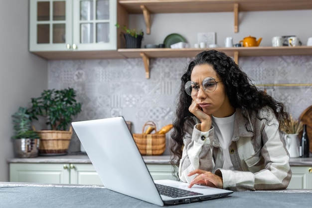 Boring and unmotivated online learning sad young beautiful female student sitting in the kitchen at