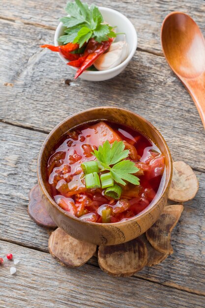 Borsch, beetroot soup in a wooden bowl with fresh herbs 