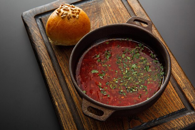 Foto borsch in een gietijzeren plaat en brood op een houten bord geïsoleerd op een zwarte achtergrond