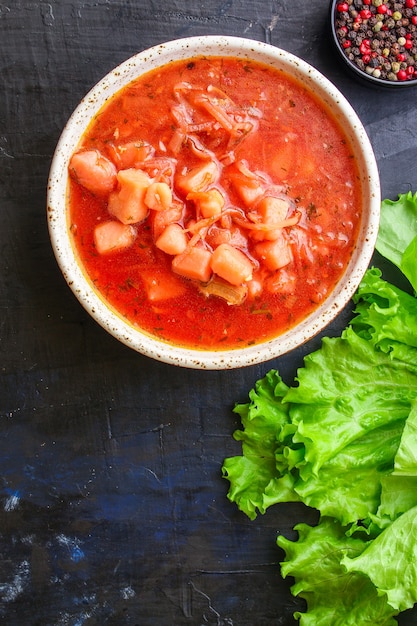 ボルシチの赤いトマトスープの最初のコースのブイヨンの肉と野菜