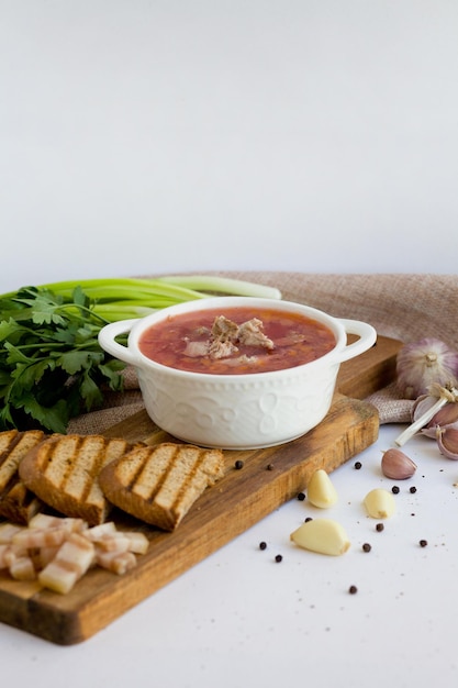 Borscht Traditional Russian red vegetable soup made of beets with croutons greens meat and lard Dish on a wooden board side view