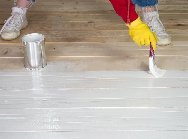 Borstel met witte verf in de hand van een meisje close-up het meisje schildert een houten oppervlak